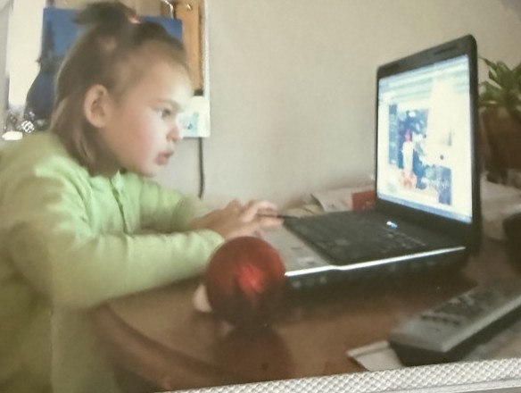 Rena as a kid, focused on a laptop